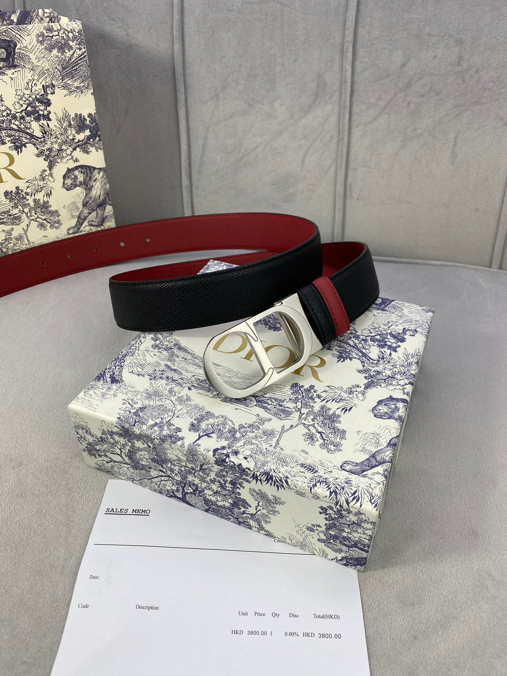 Dior belt: black strap with red trim and silver-tone oval buckle.