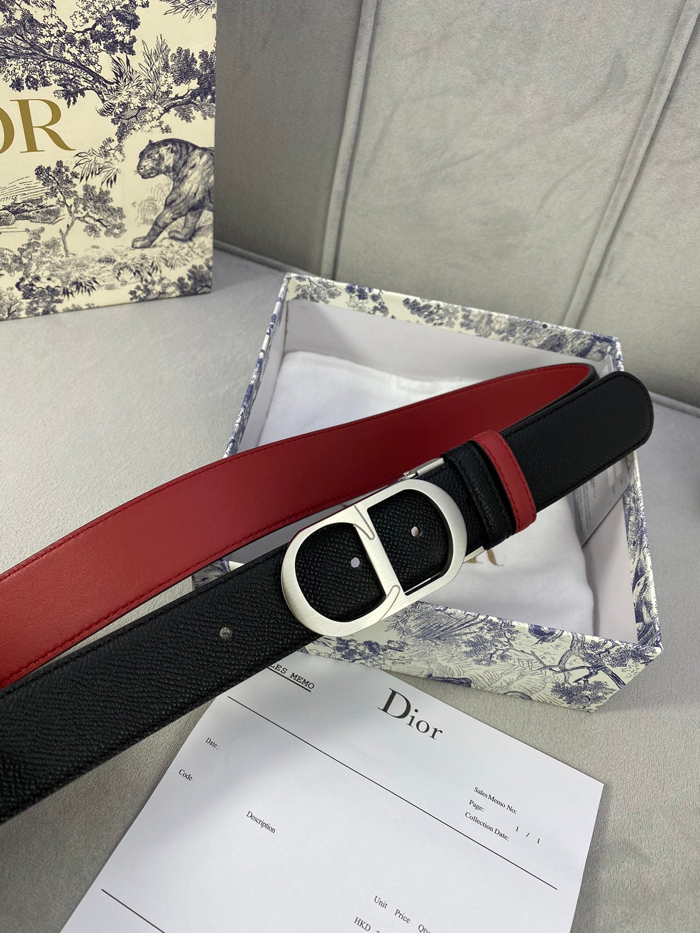 Dior belt extended: black strap with red lining and silver-tone oval buckle.