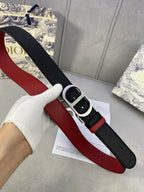 Dior belt with black strap and red stripe, silver-tone buckle; held in hand.