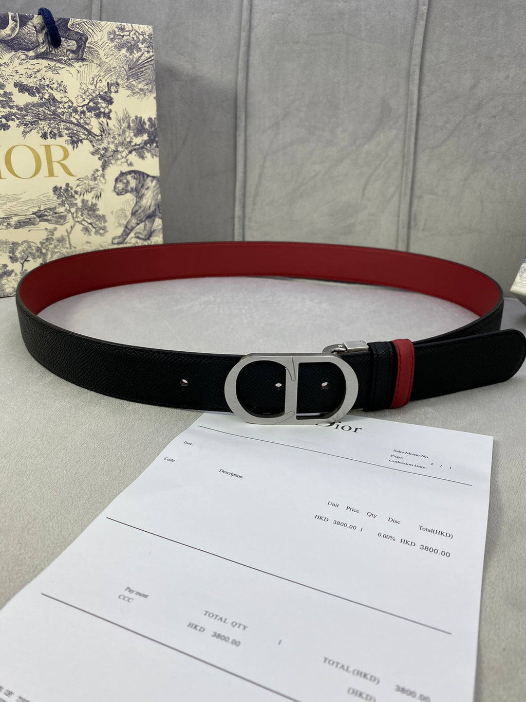 Dior belt with black textured strap, red edge, silver-tone oval buckle.