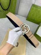 Gucci belt beige leather with silver G buckle, held in hand over dust bag