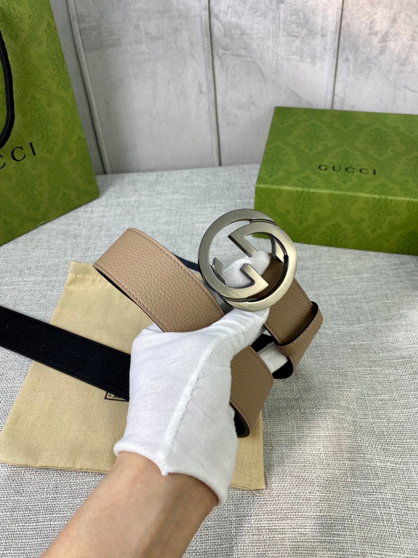 Gucci belt beige leather and silver double-G buckle, held above dust bag