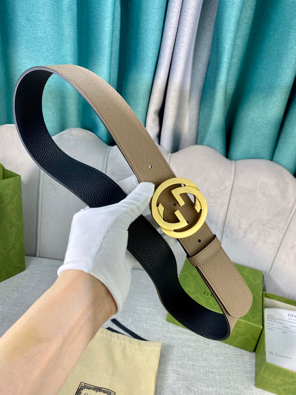 Gucci belt beige leather with gold double-G buckle and black underside, laid on fabric