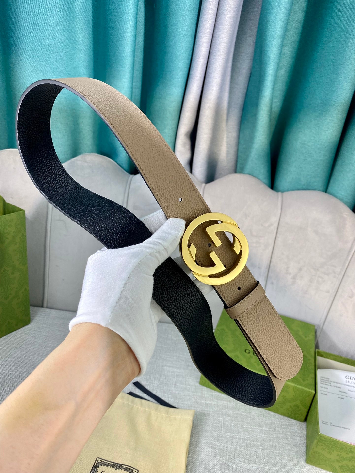 Gucci belt beige leather with gold double-G buckle and black underside, laid on fabric