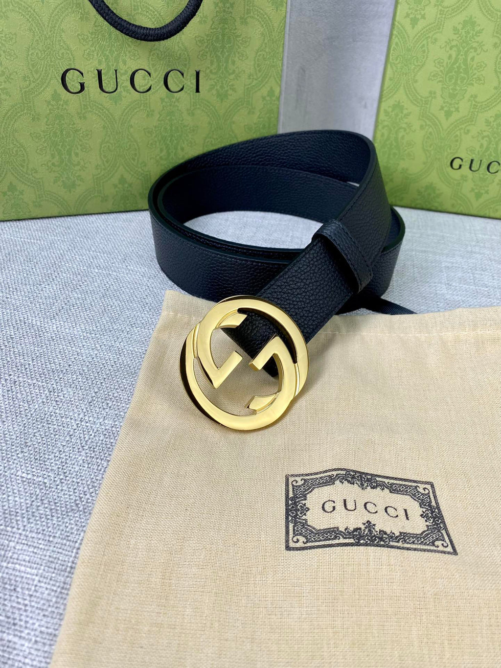 Black leather belt with gold-tone interlocking GG buckle on folded fabric.