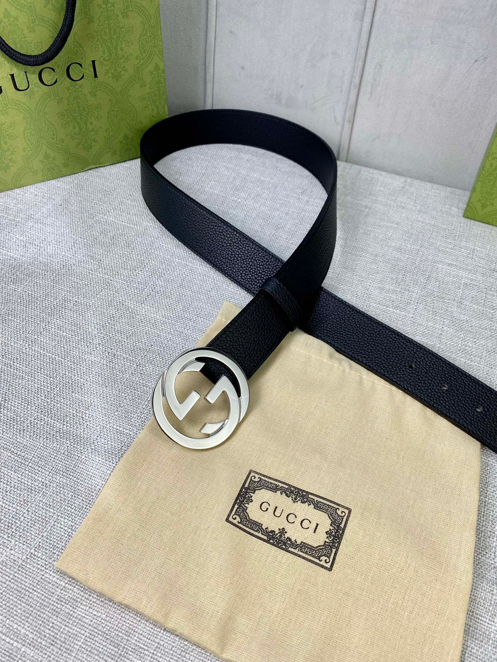 Black leather belt with gold-tone interlocking GG buckle on dust bag.