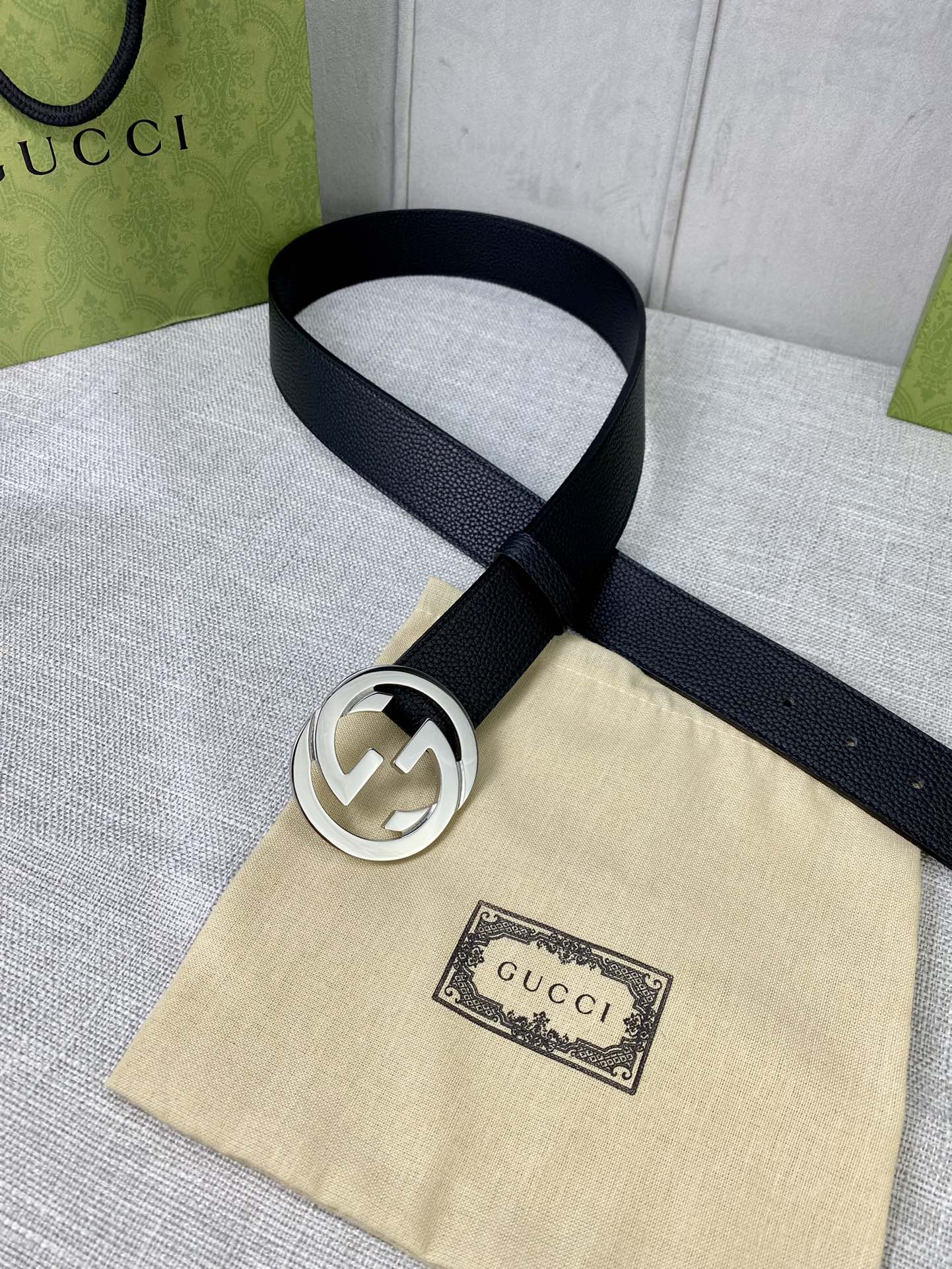 Black leather belt with gold-tone interlocking GG buckle on dust bag.