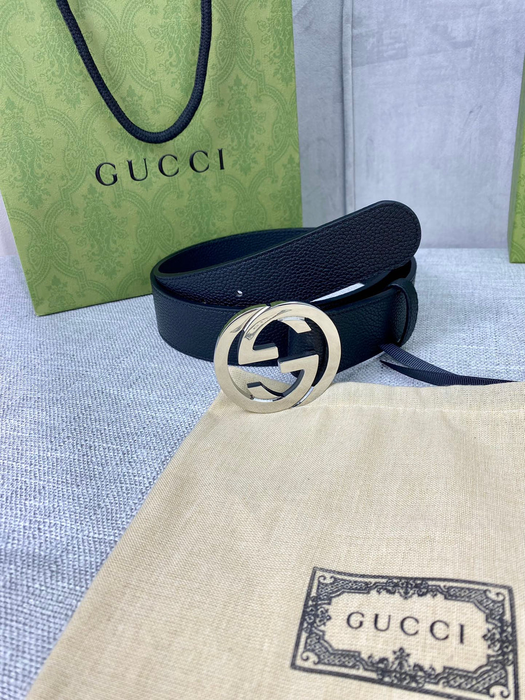 Black leather belt with silver-tone interlocking GG buckle on cloth.