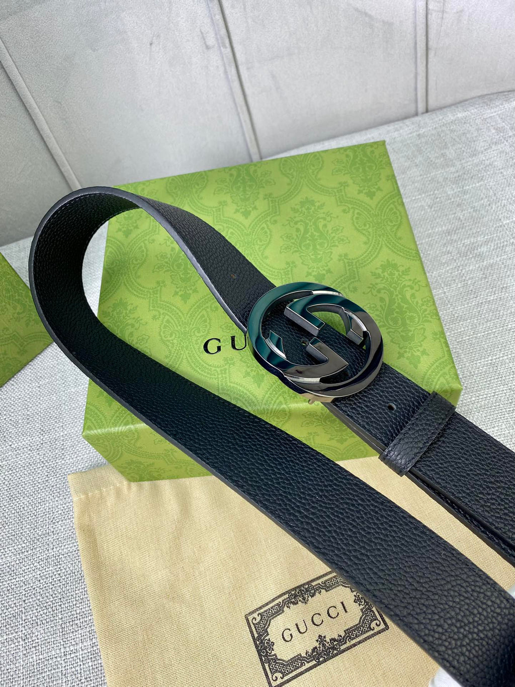 Black leather belt with gold-tone interlocking GG buckle, close-up.