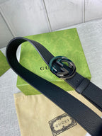 Black leather belt with gold-tone interlocking GG buckle, close-up.