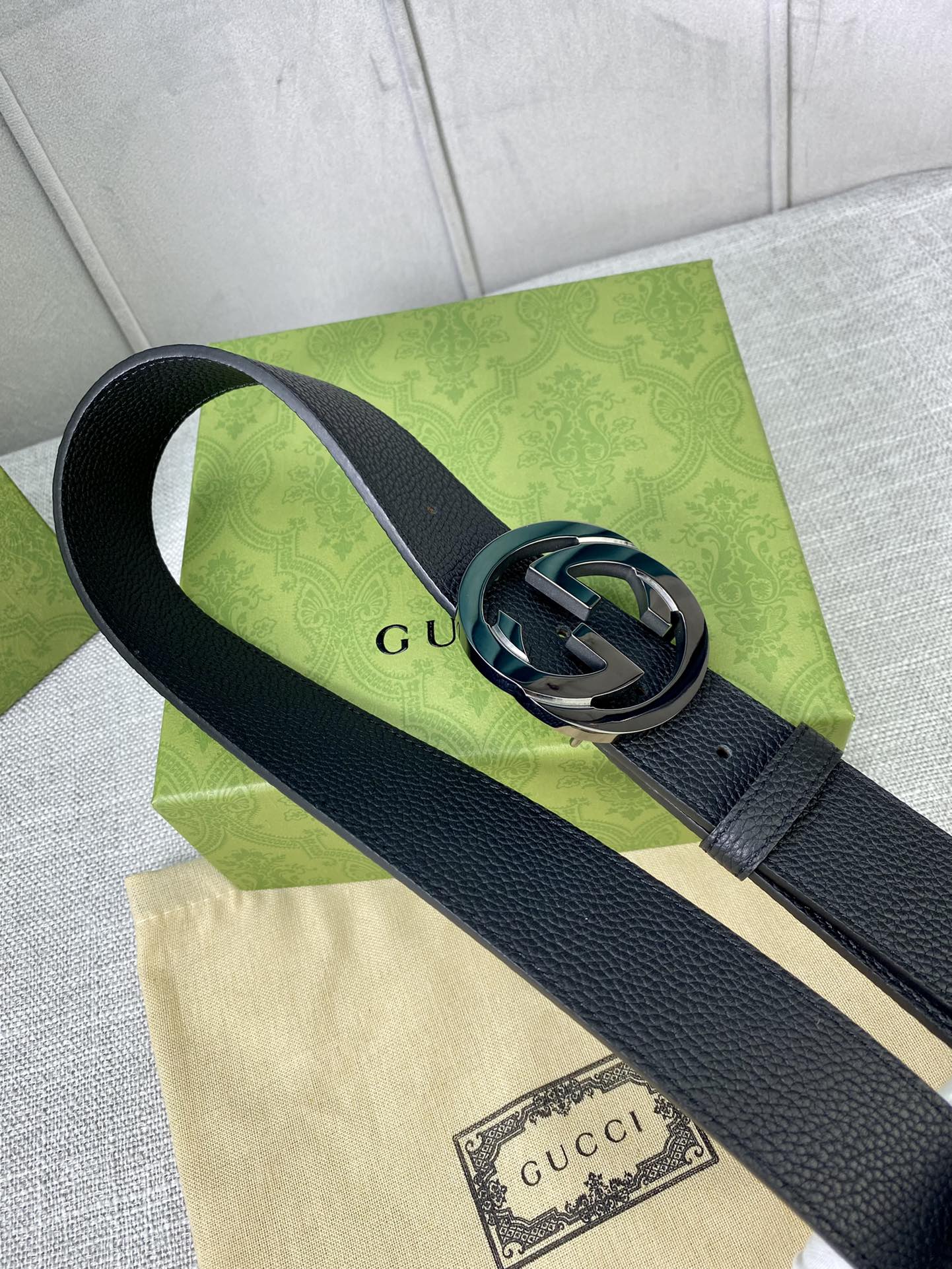 Black leather belt with gold-tone interlocking GG buckle, close-up.
