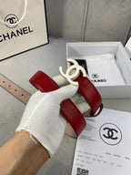 Red leather Chanel belt with gold-tone CC buckle, held by gloved hand