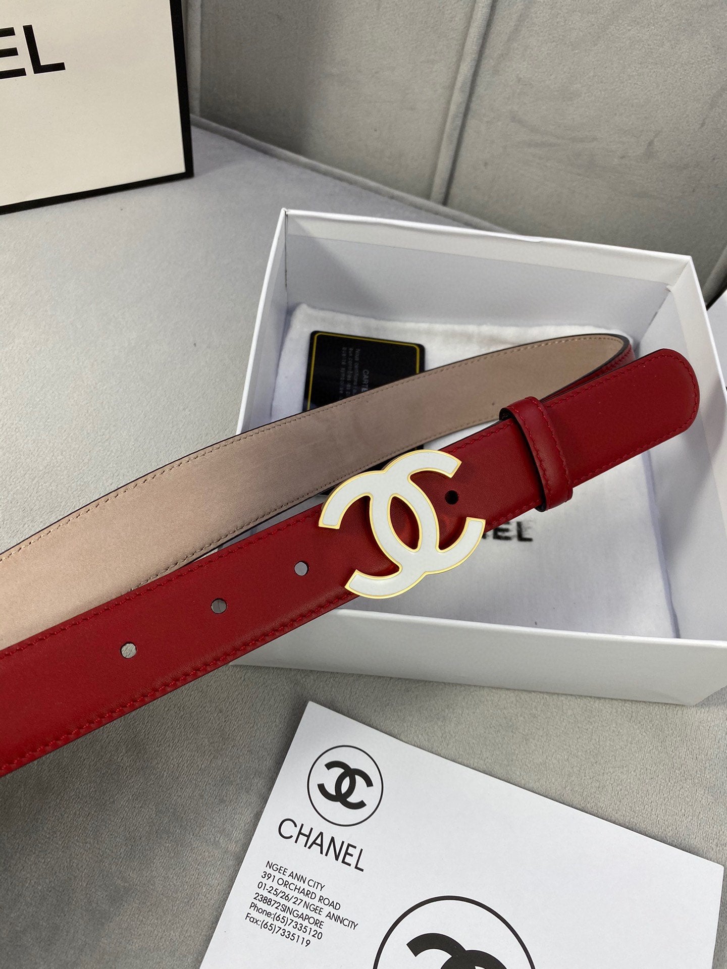 Red leather Chanel belt with gold-tone CC buckle, shown in gift box
