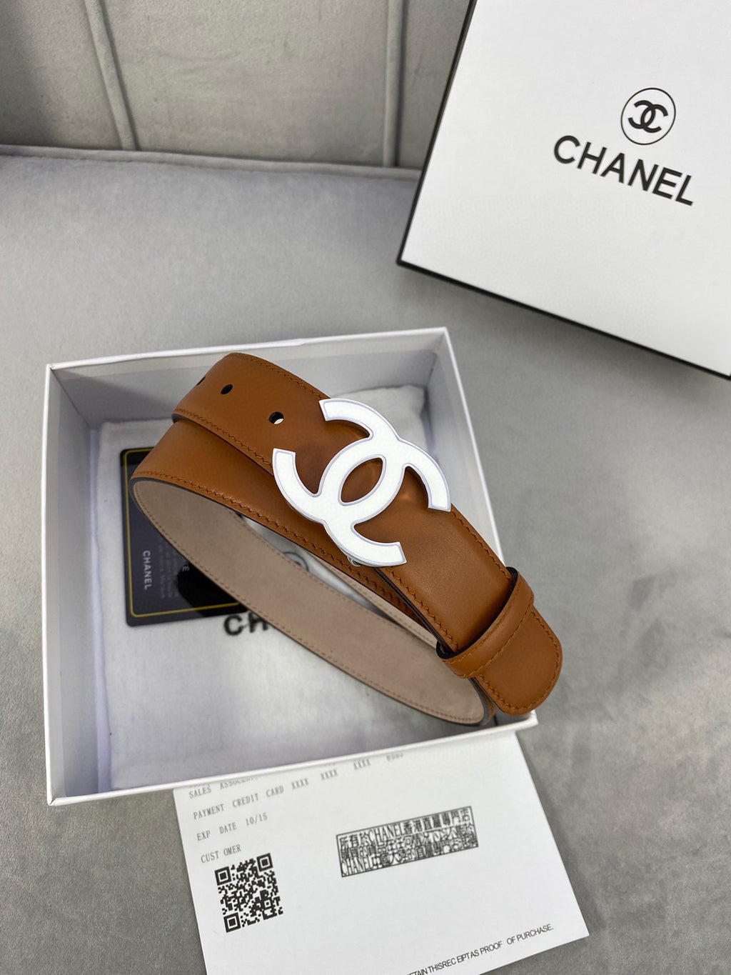 Chanel tan leather belt with gold-tone CC buckle resting in a gift box