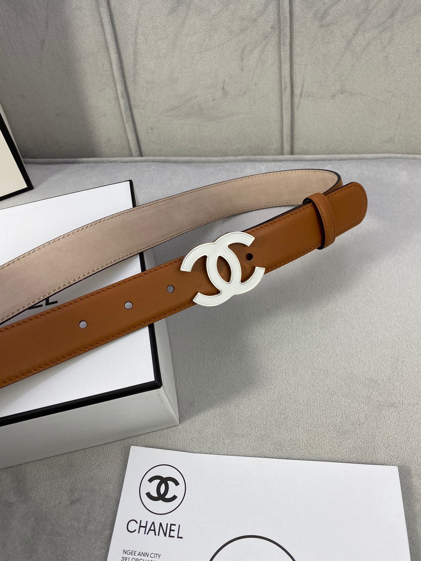 Tan Chanel leather belt detail with gold-tone CC buckle and multiple punched holes