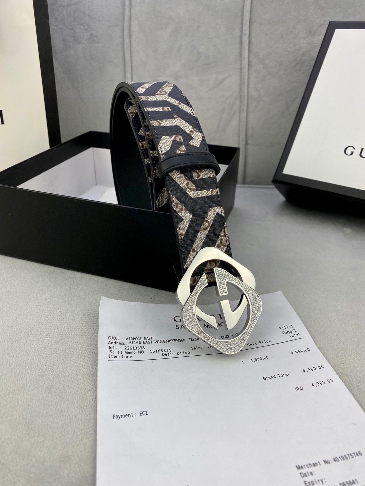 Gucci belt angled view: navy/beige GG strap with metallic interlocking G buckle