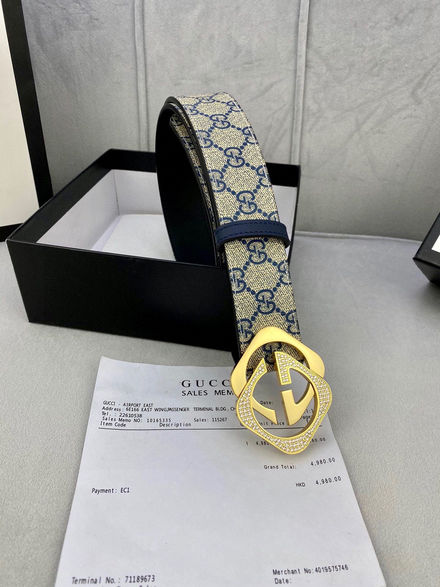 GG monogram belt end view with blue strap, gold-tone buckle, and black underside
