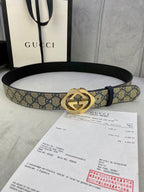 Belt with blue GG monogram strap and gold-tone buckle laid over documents