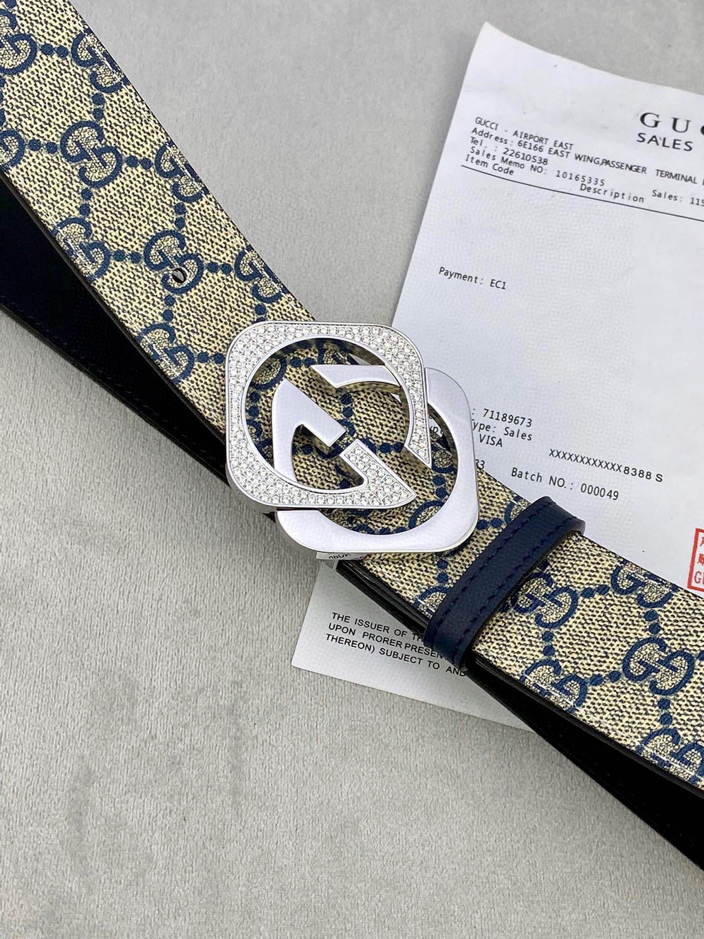 GG monogram belt close-up with navy canvas strap and textured silver buckle