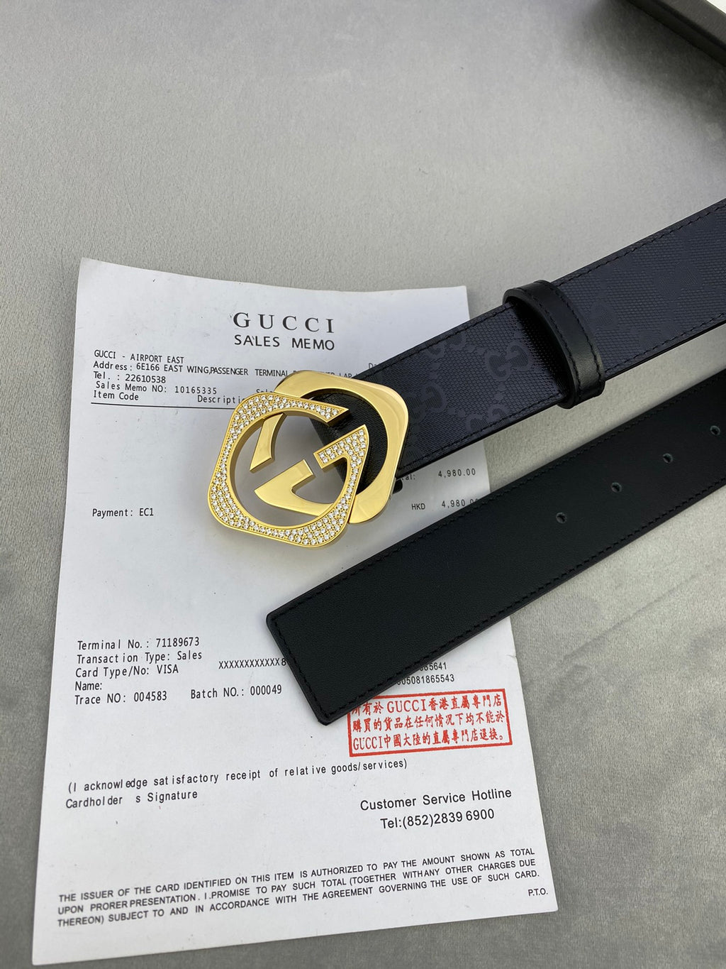 Gucci belt with dark leather strap and gold interlocking buckle on a flat lay.