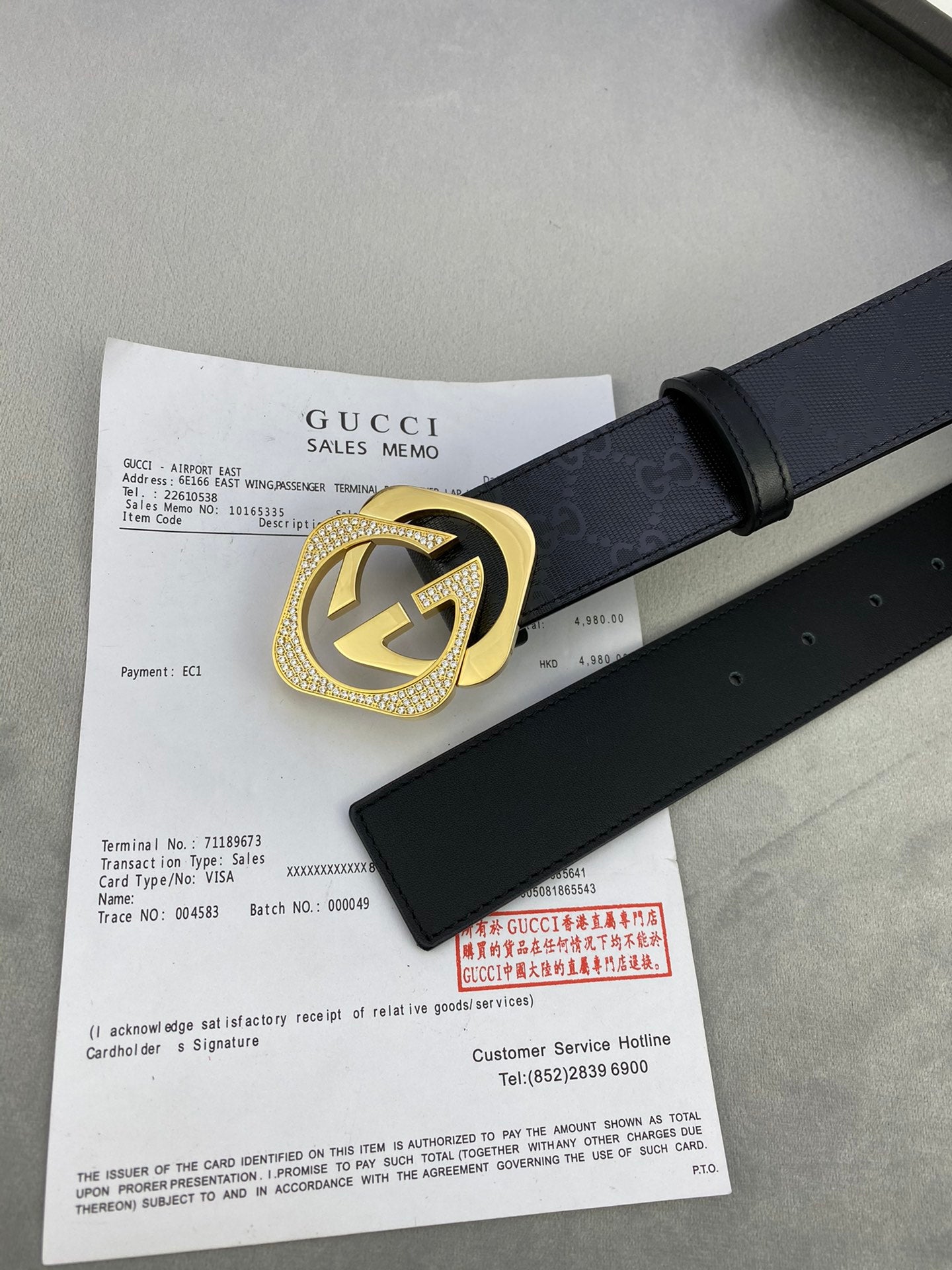 Gucci belt with dark leather strap and gold interlocking buckle on a flat lay.