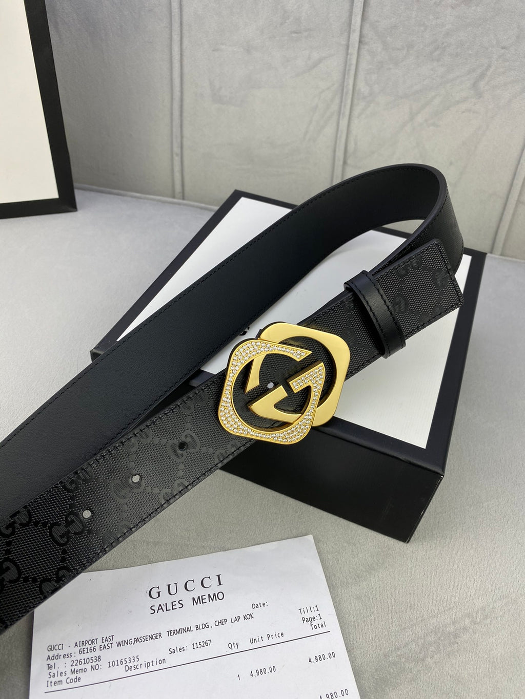 Gucci belt with dark leather strap and gold interlocking emblem buckle detail.