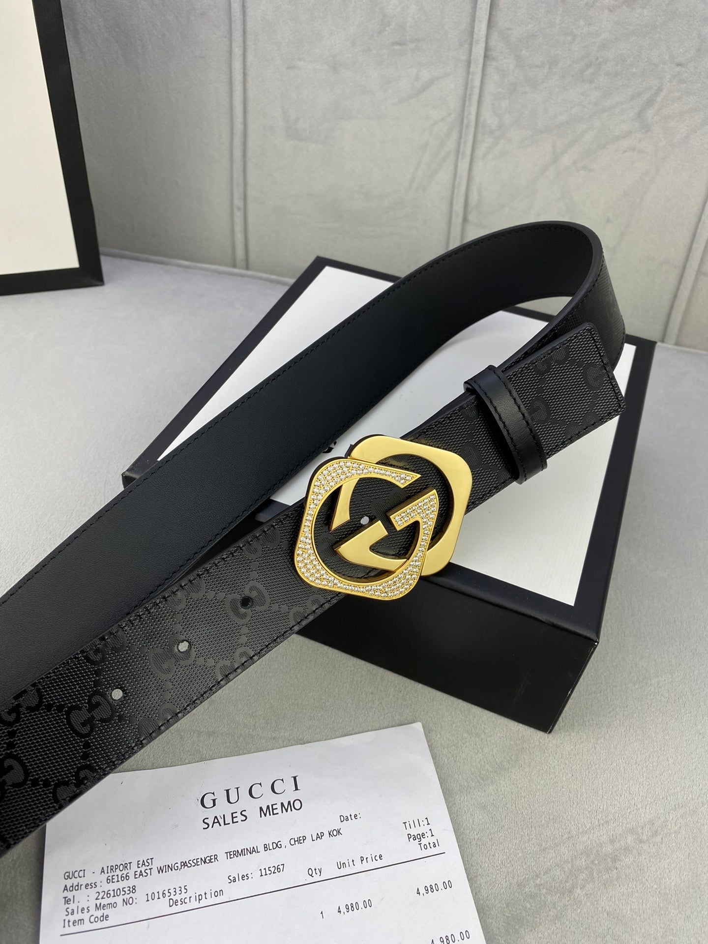 Gucci belt with dark leather strap and gold interlocking emblem buckle detail.
