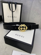 Gucci belt with dark leather strap and gold interlocking buckle, centered on box lid.