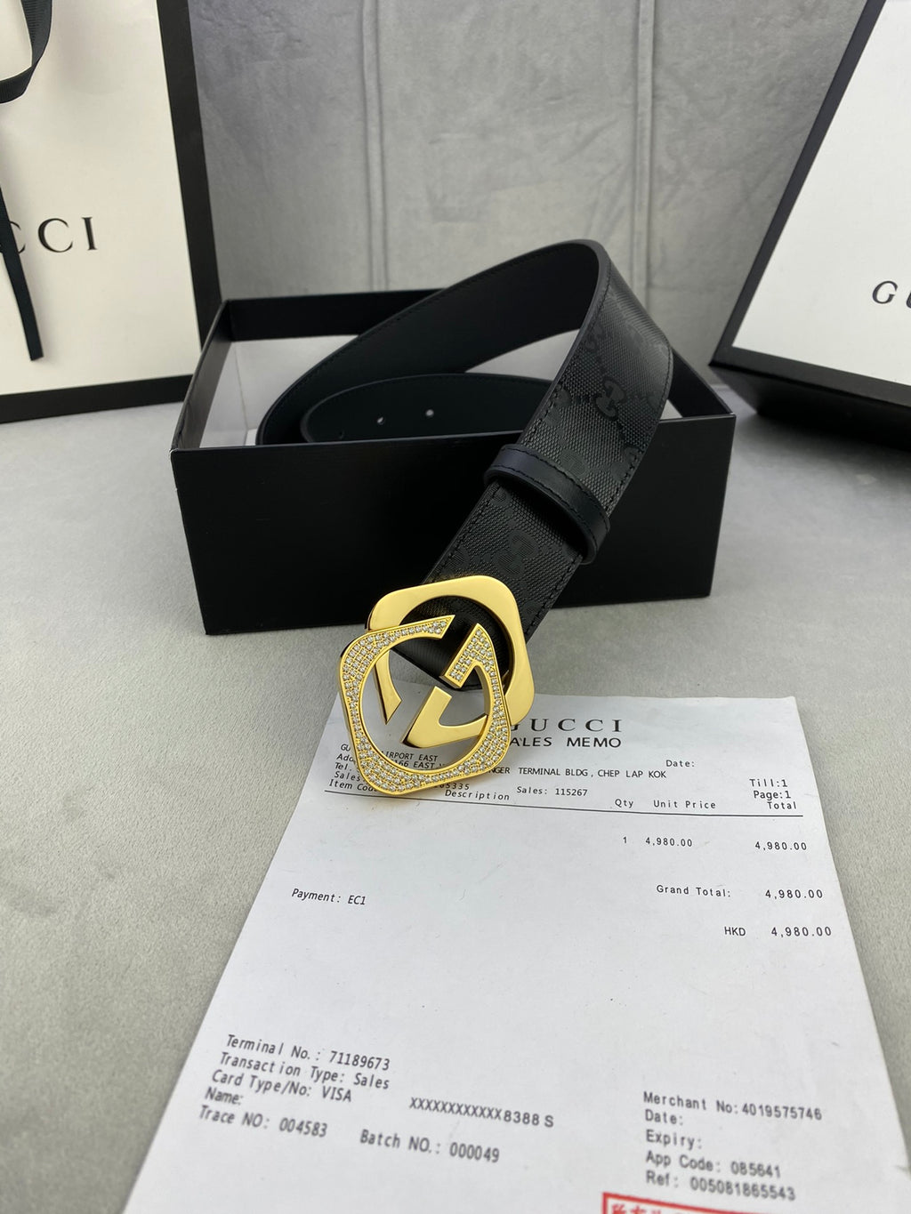 Gucci belt with dark leather strap and gold interlocking buckle, studded strap end.