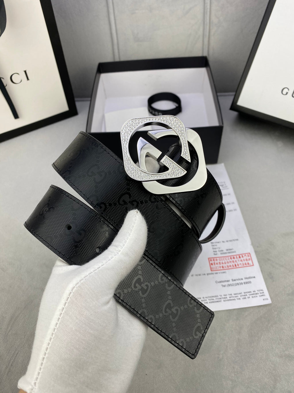 Gucci belt with dark leather strap and large silver interlocking buckle, end detail.