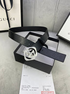 Gucci belt with dark leather strap and silver interlocking buckle, strap tip visible.