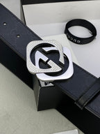 Gucci belt close-up with dark leather strap and large silver interlocking buckle.