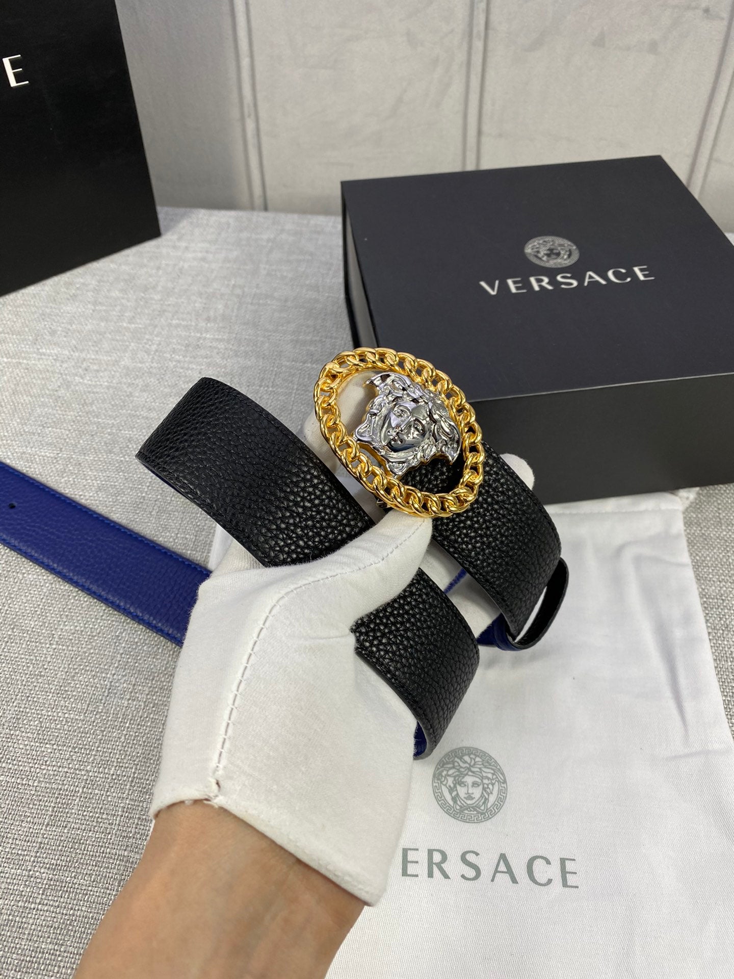 Leather belt with black textured strap and gold Medusa medallion buckle