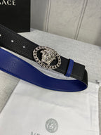 Leather belt close-up with blue strap, black textured band, silver Medusa buckle