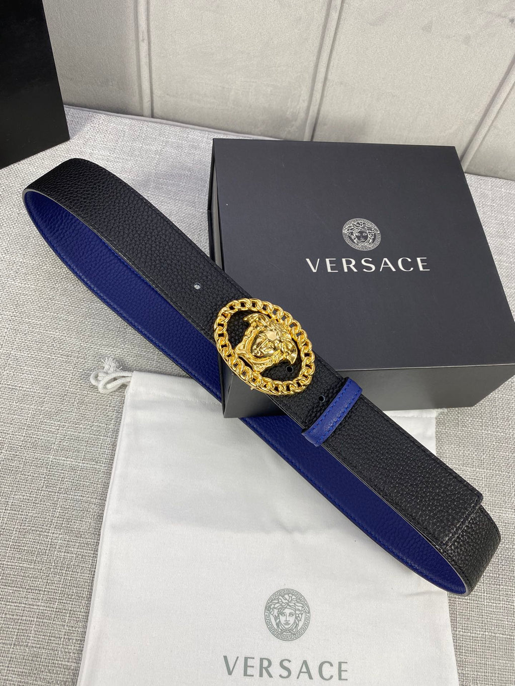 Leather belt with black textured strap, blue edge, gold Medusa buckle