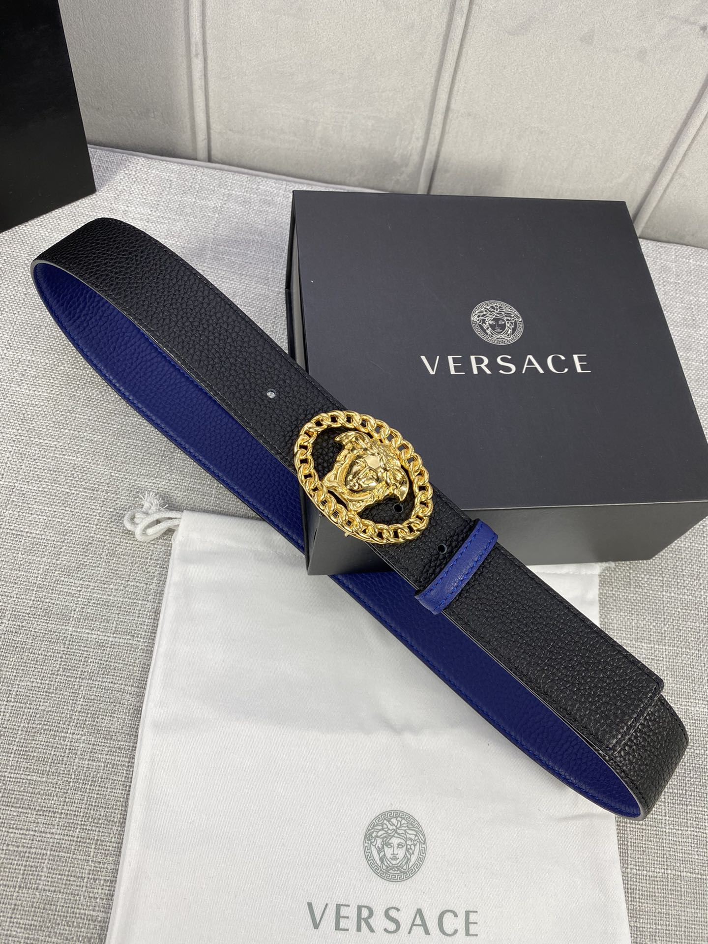 Leather belt with black textured strap, blue edge, gold Medusa buckle