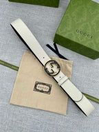 Gucci belt with white strap and round black GG buckle, flat view on dust bag