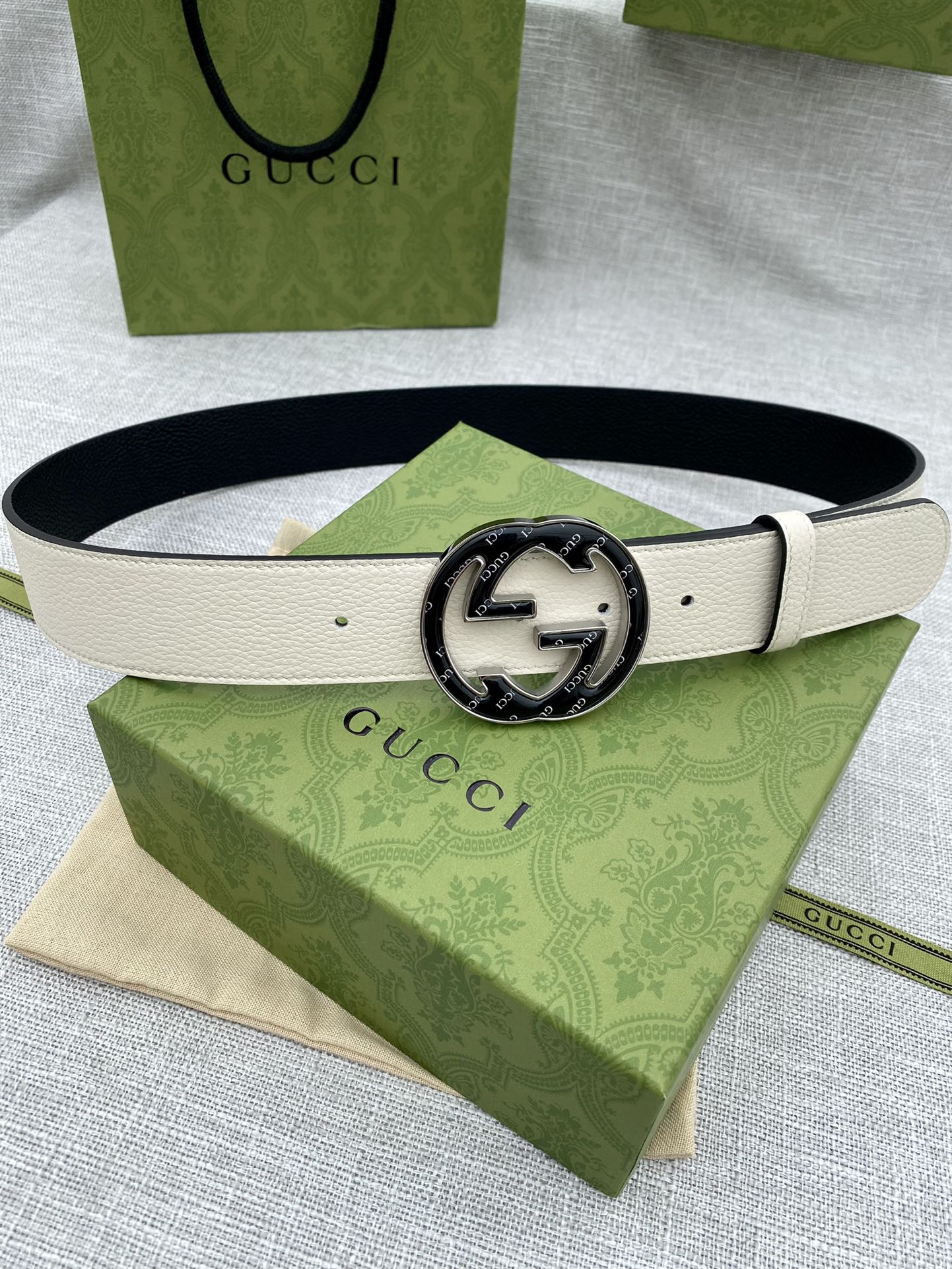 Gucci belt with white leather strap and round black GG logo buckle