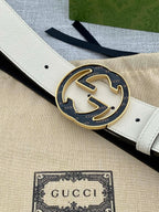 Gucci belt buckle detail: round black GG logo on white strap