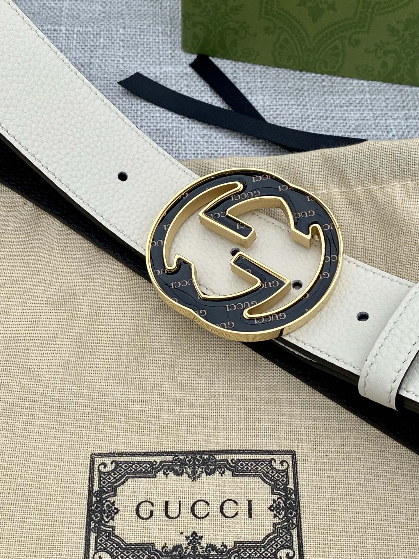 Gucci belt buckle detail: round black GG logo on white strap