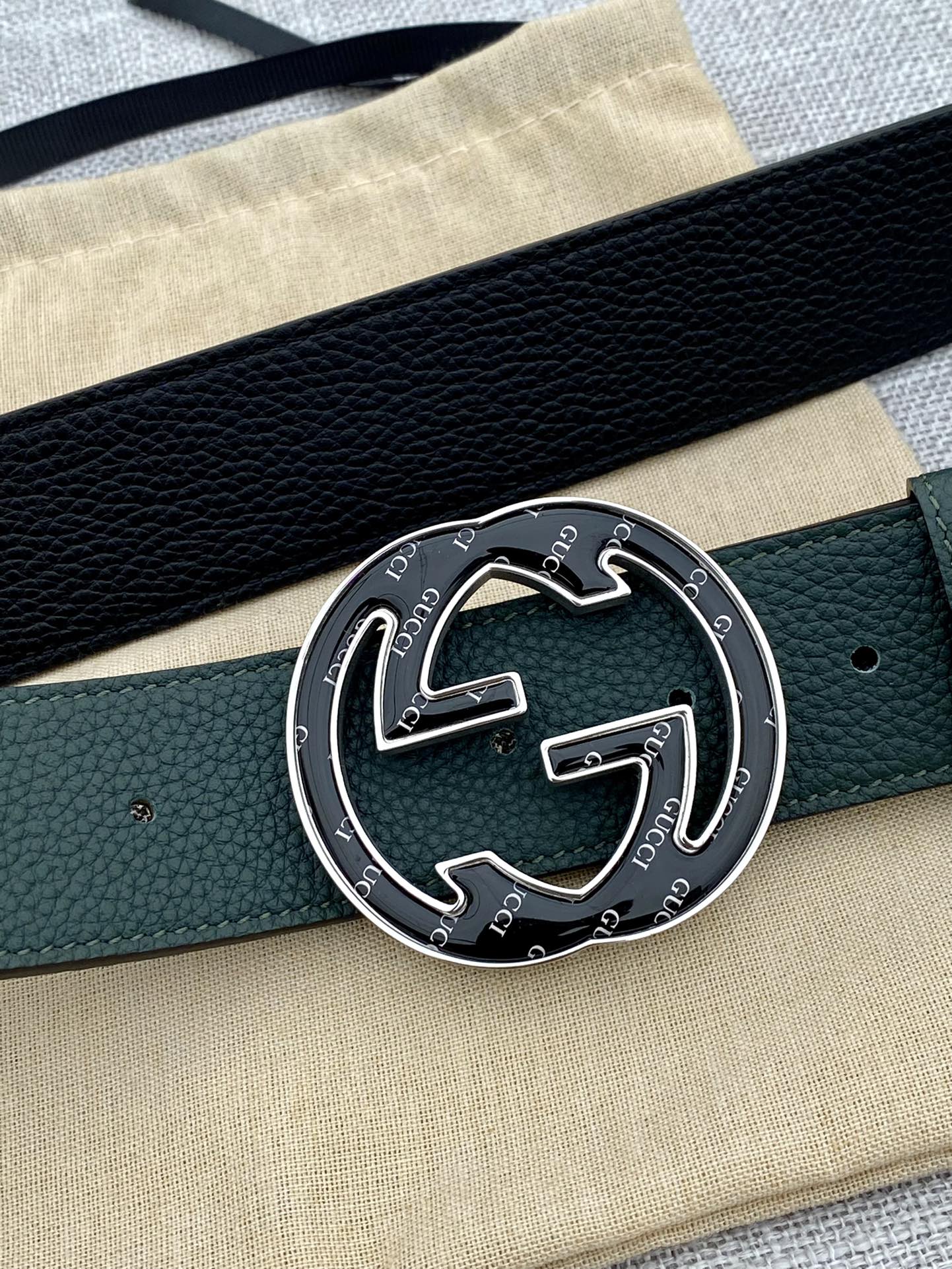 Close-up of dark green leather belt with round GG logo buckle in gold-tone metal