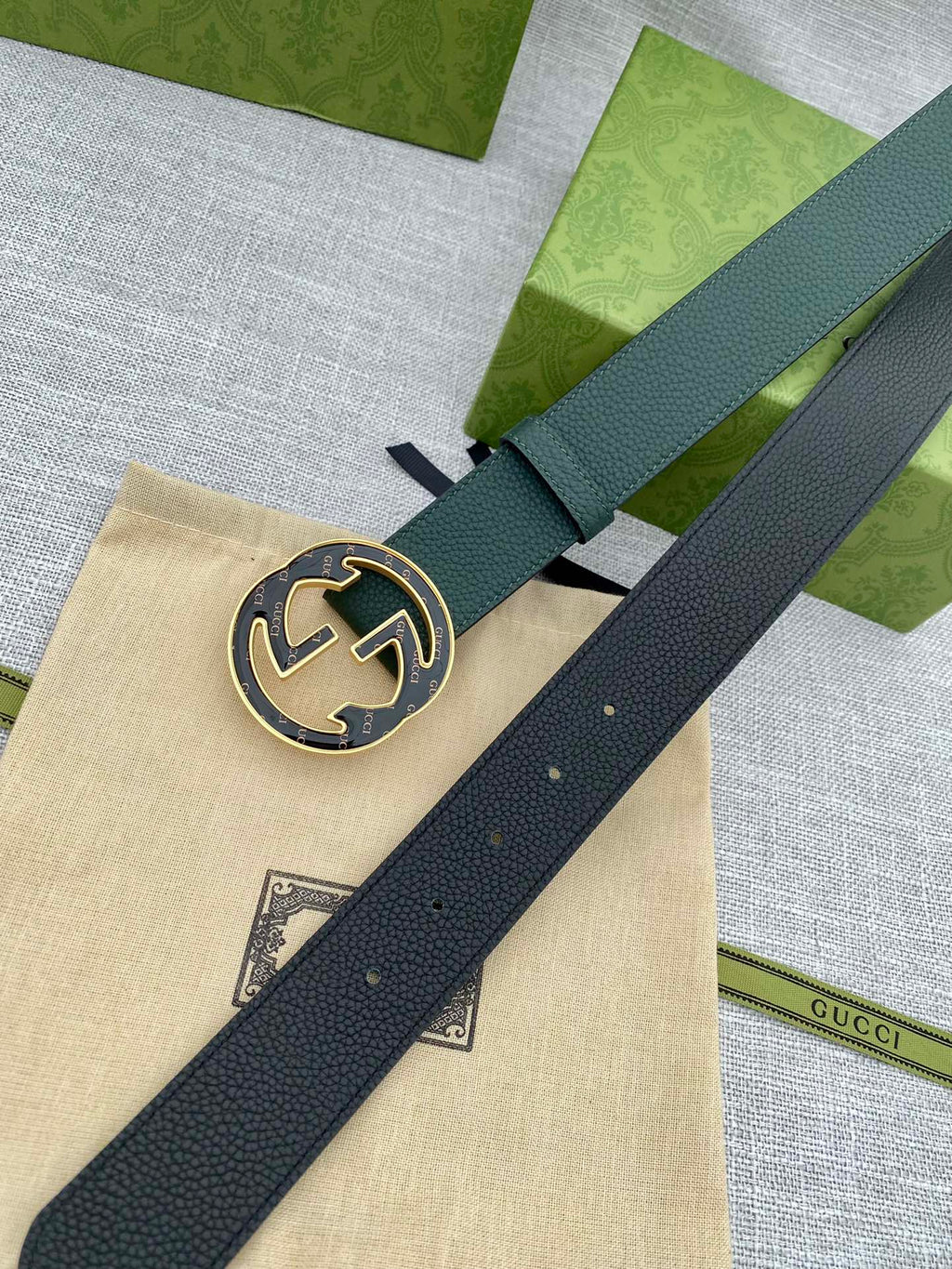 Dark green leather belt with round GG logo buckle, close-up on center plate