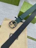 Dark green leather belt with round GG logo buckle, close-up on center plate
