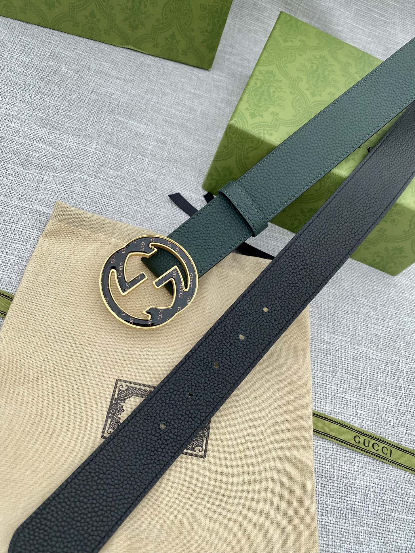 Dark green leather belt with round GG logo buckle, close-up on center plate