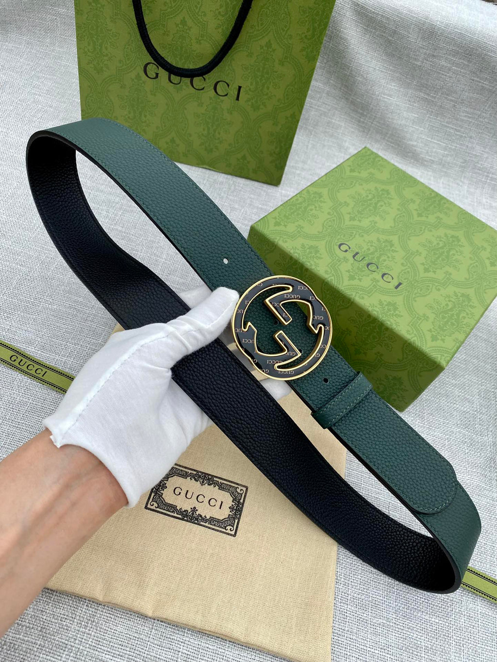 Dark green leather belt with round GG logo buckle, shown on hand for fit