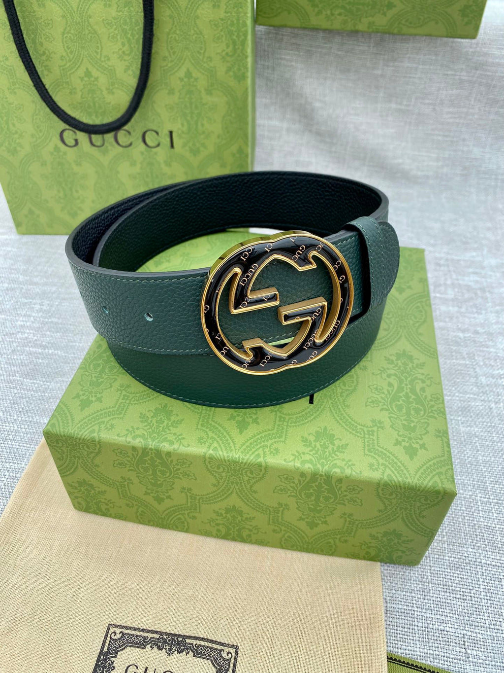 Dark green leather belt with round GG logo buckle and gold-tone bezel