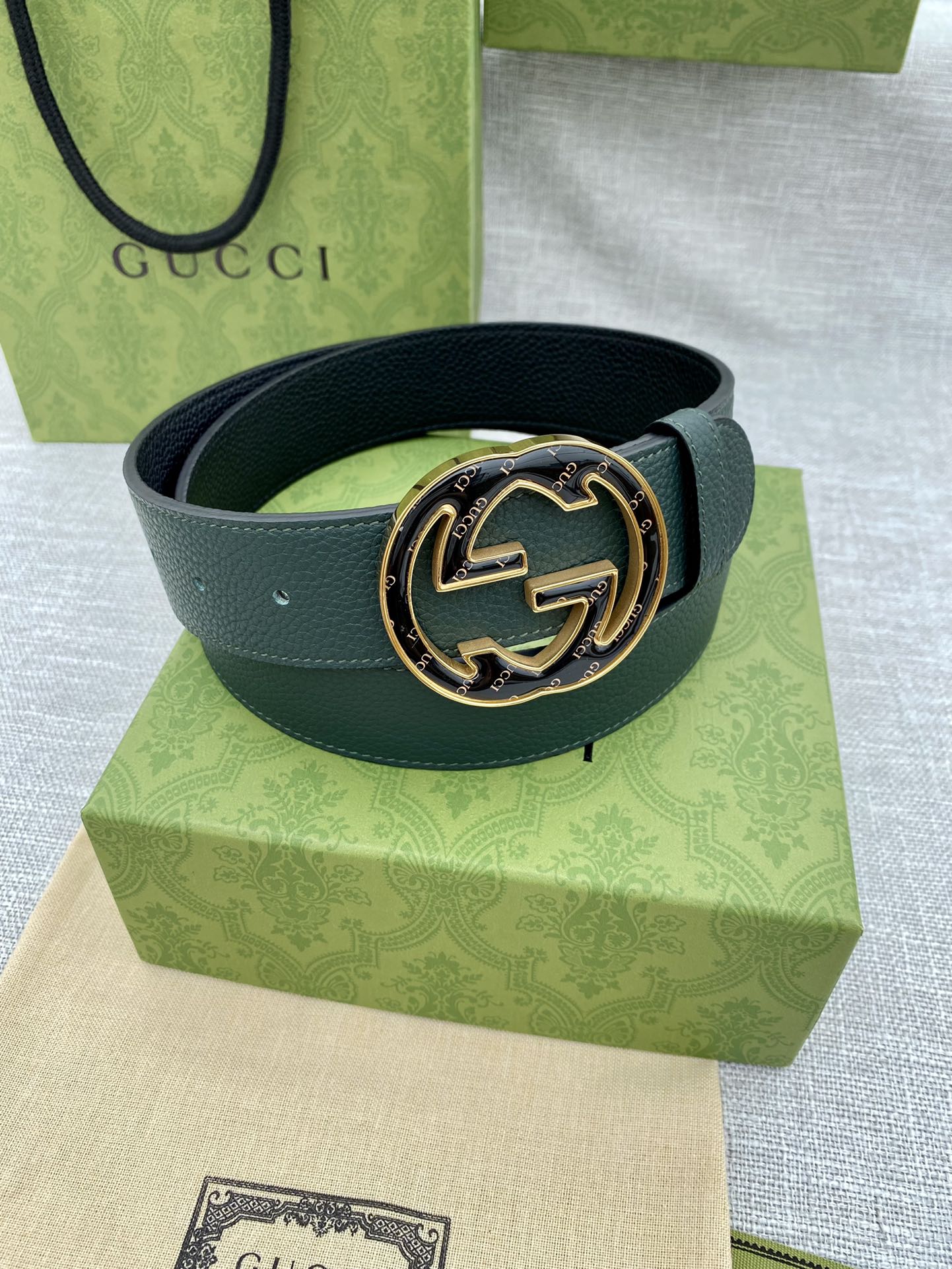 Dark green leather belt with round GG logo buckle and gold-tone bezel