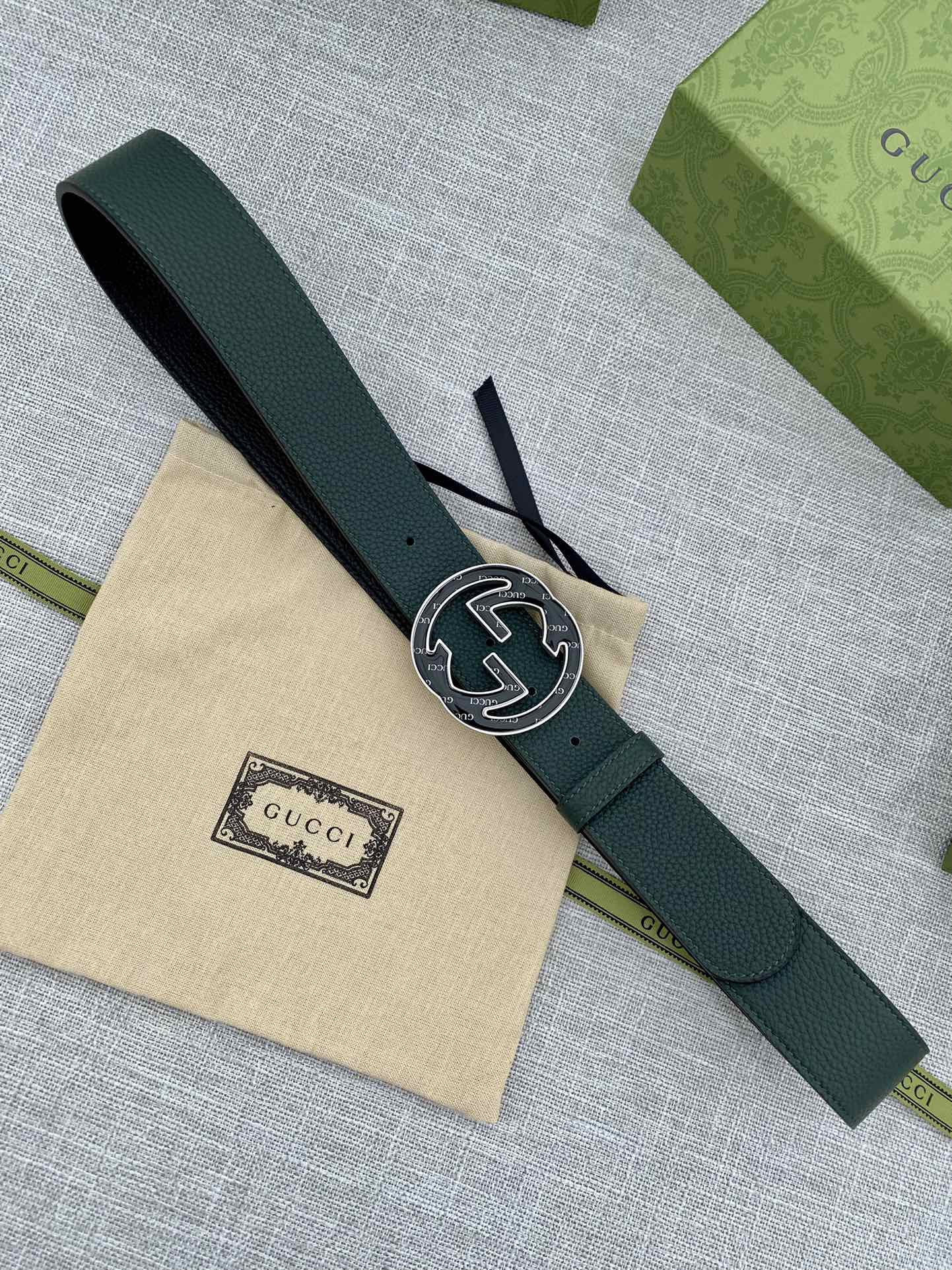 Dark green leather belt with round GG logo buckle, strap and buckle in view