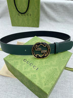 Dark green leather belt with round GG logo buckle, gold-tone edges and dark enamel