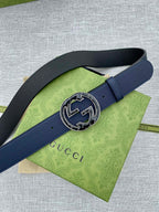 Navy blue leather belt with round double-G logo buckle on green tissue